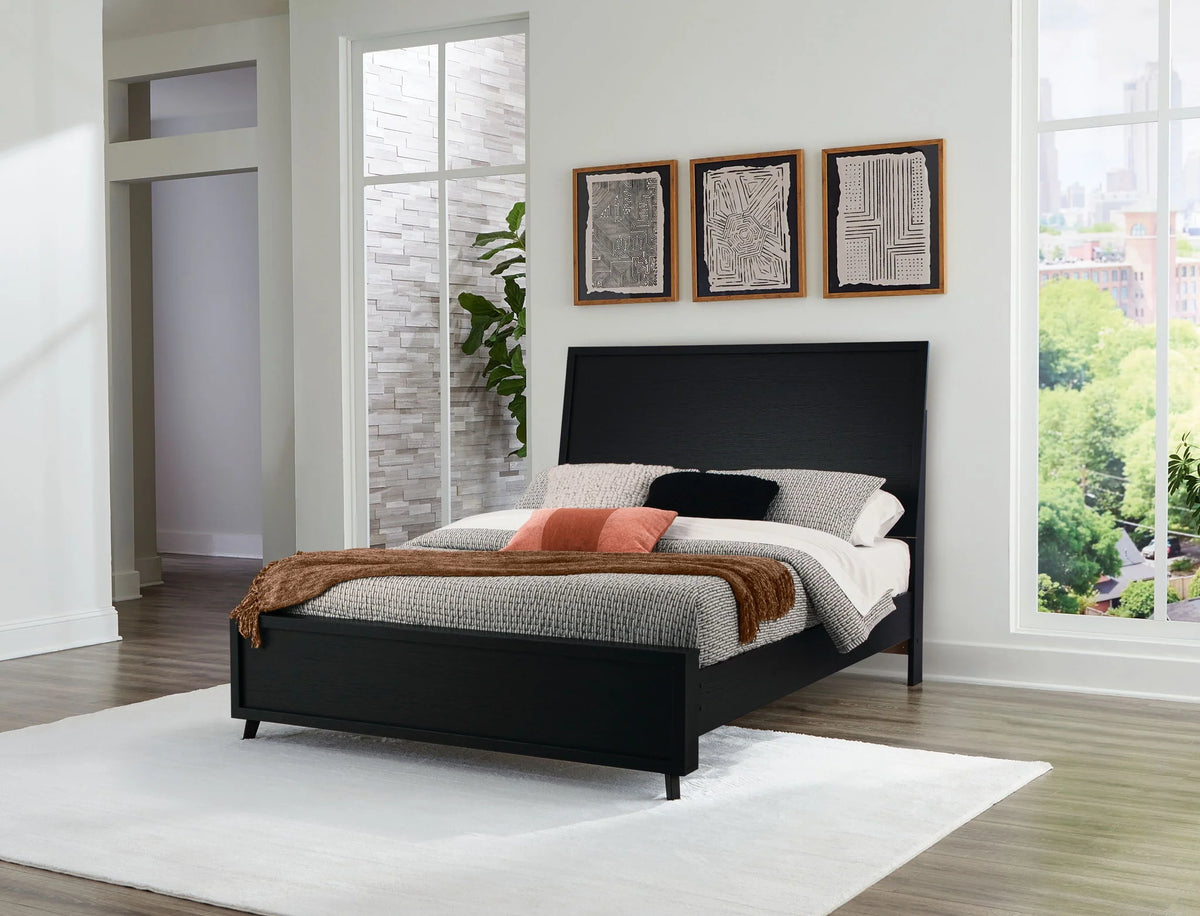 Danziar black panel bed with a tall headboard and low footboard in a bright bedroom