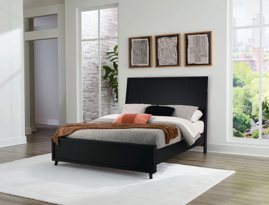 Danziar black panel bed with a tall headboard and low footboard in a bright bedroom