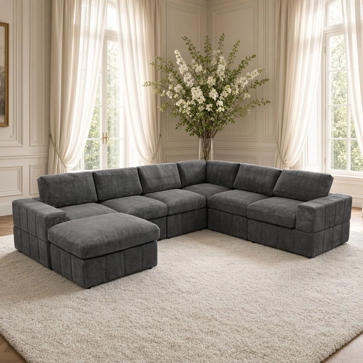 Dark gray modular corner sectional with a matching ottoman arranged as a chaise in a living room