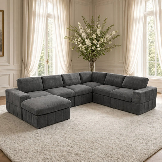 Dark gray modular corner sectional with a matching ottoman arranged as a chaise in a living room