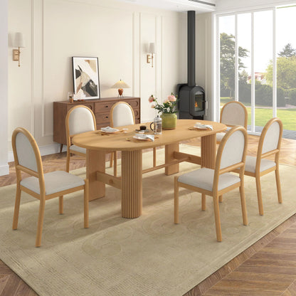 Light brown oval dining table with fluted supports and six beige upholstered round-back chairs