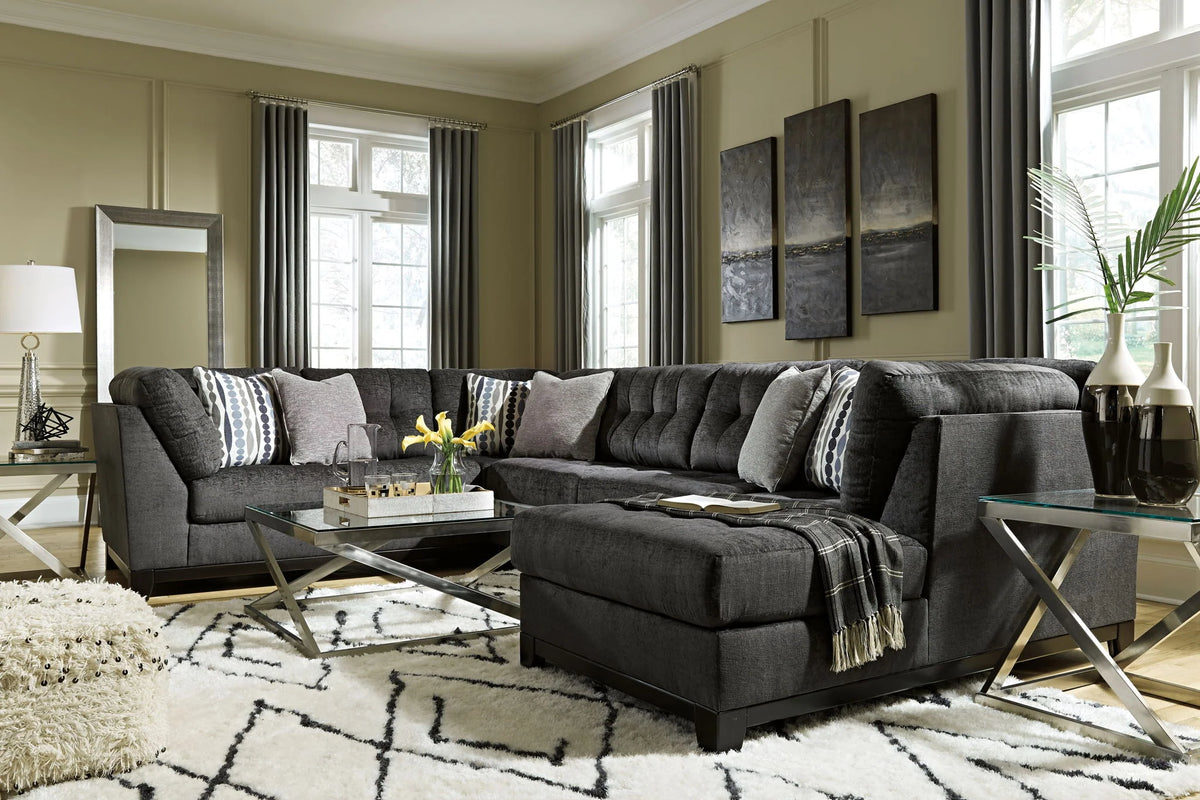 Reidshire steel gray chaise sectional beside glass tables with a patterned rug and accent pillows